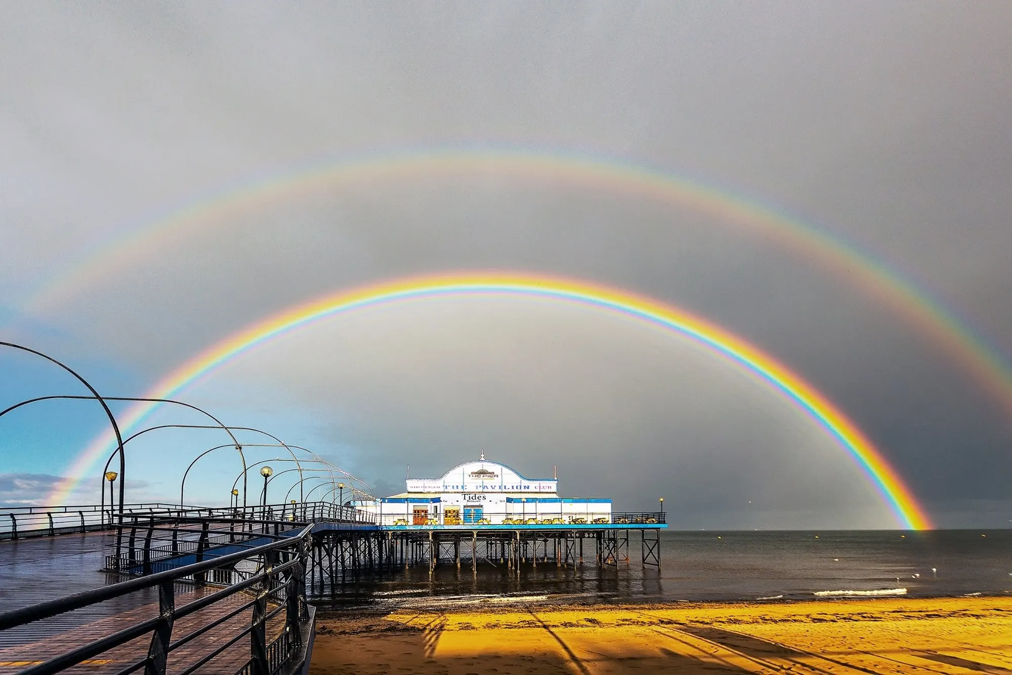 A double rainbow arching over Cleethorpes Pier and the beach after a storm