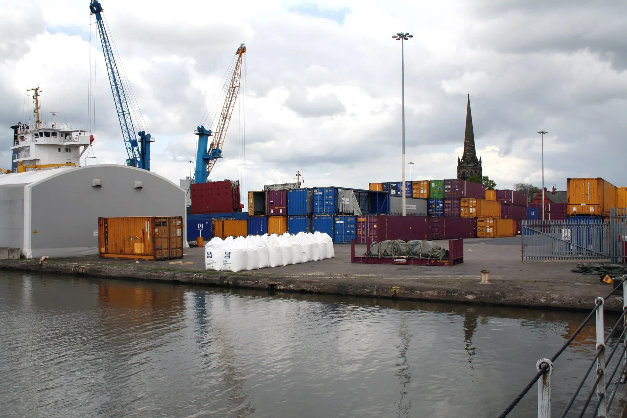 Cranes, shipping containers and a moored vessel at Aldam Dock, Goole, with the church spire in the background