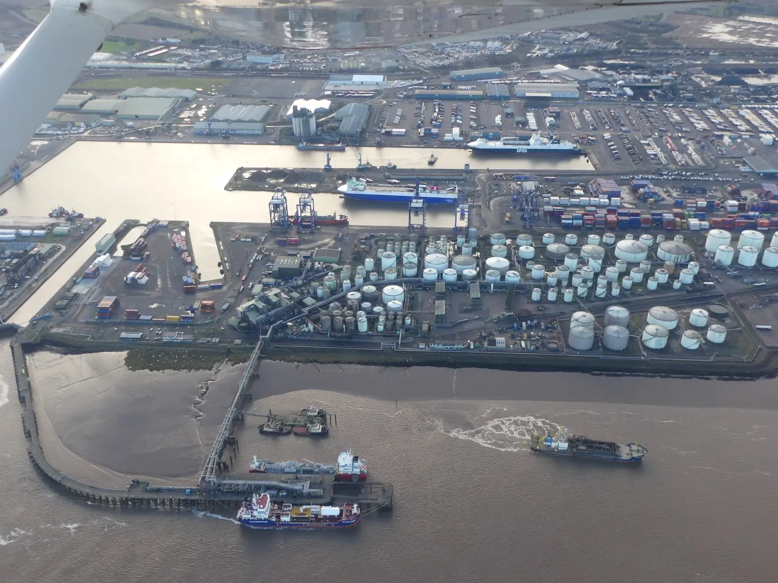 Oblique aerial view of the Port of Immingham on the Humber, showing the dock basin, oil storage tanks, the oil jetty and ships alongside