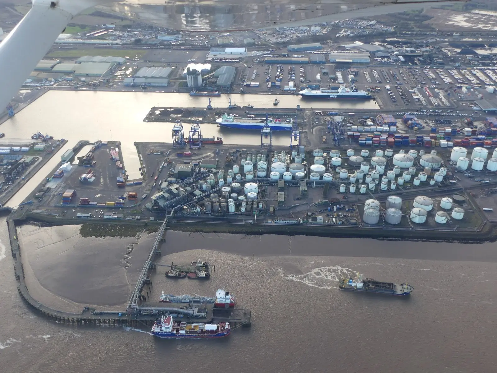 Oblique aerial view of the Port of Immingham on the Humber, showing the dock basin, oil storage tanks, the oil jetty and ships alongside