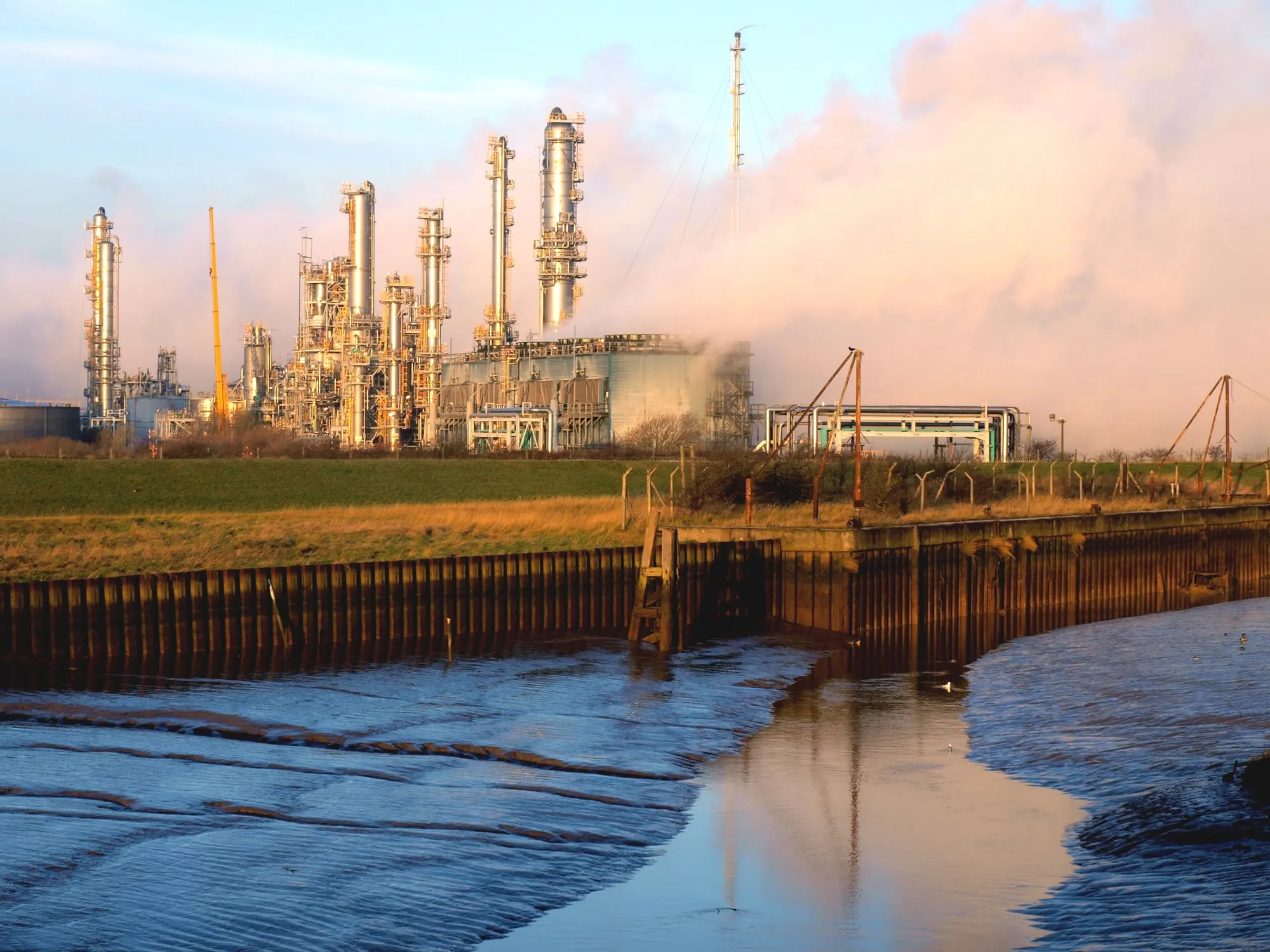 Saltend Chemicals Park near Hull at golden hour, with distillation columns and steam rising beyond the mouth of Hedon Haven